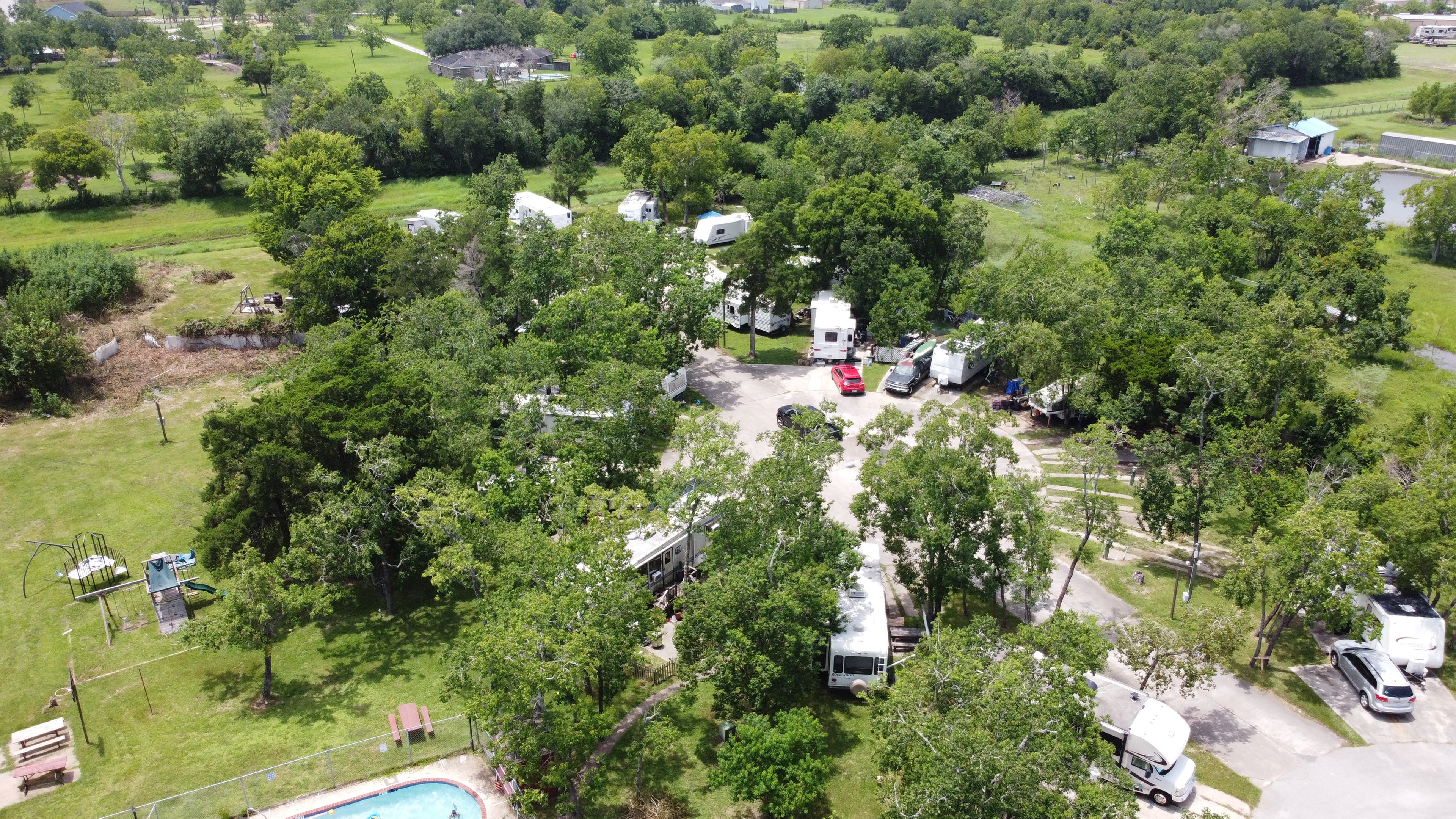 Aerial drone photo of Little Thicket RV Resort showing pool and shaded sites